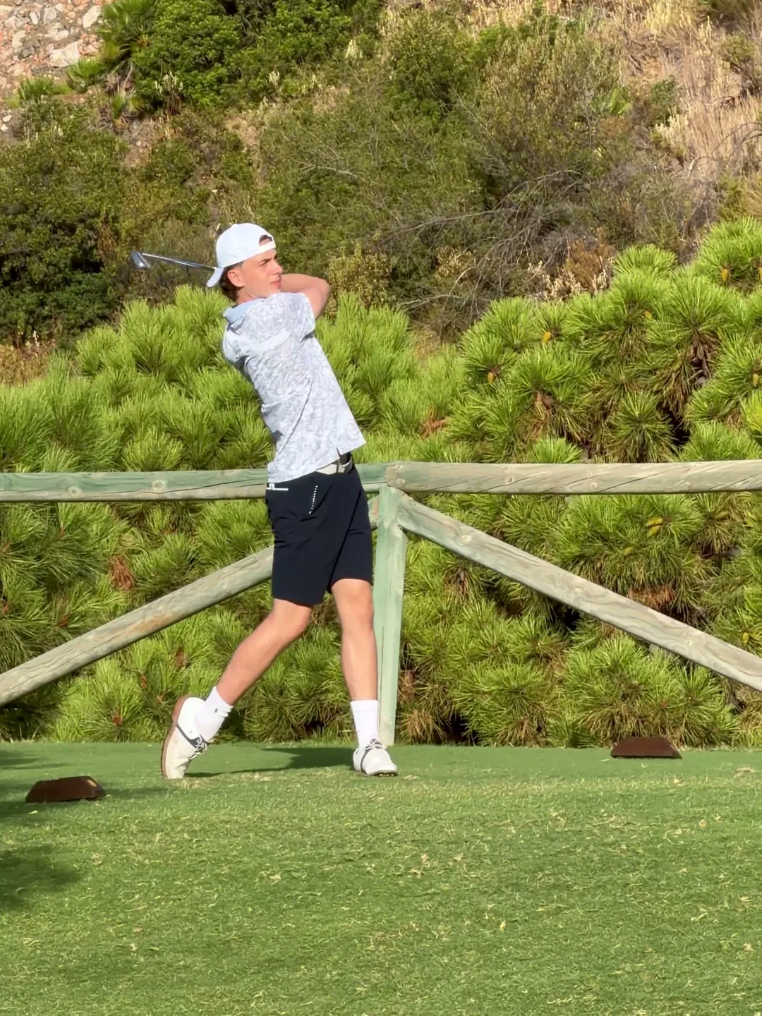 A golfer holding his finish after a full swing on the tee.